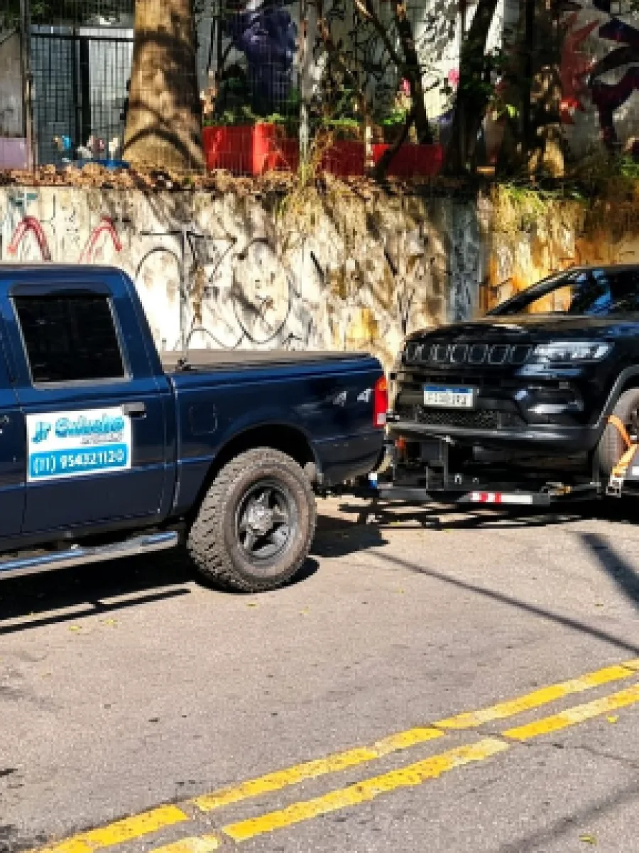 Atendimento real da JR Guincho com caminhonete azul e veículo sobre plataforma